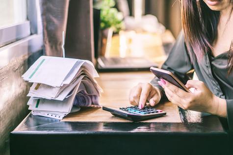 Woman Hand Calculating Her Monthly Expenses And Debt During Tax Season With Financial Bills