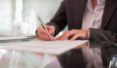 Businesswoman Writing On Paper At Desk